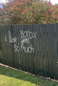 Wooden Fence at Laser Lounge Med Spa in Georgetown, Texas. With the words I love you and the word you scratched out and replaced by the word Botox in white painted on it.