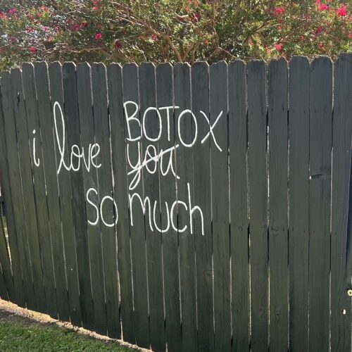 Wooden Fence at Laser Lounge Med Spa in Georgetown, Texas. With the words I love you and the word you scratched out and replaced by the word Botox in white painted on it.